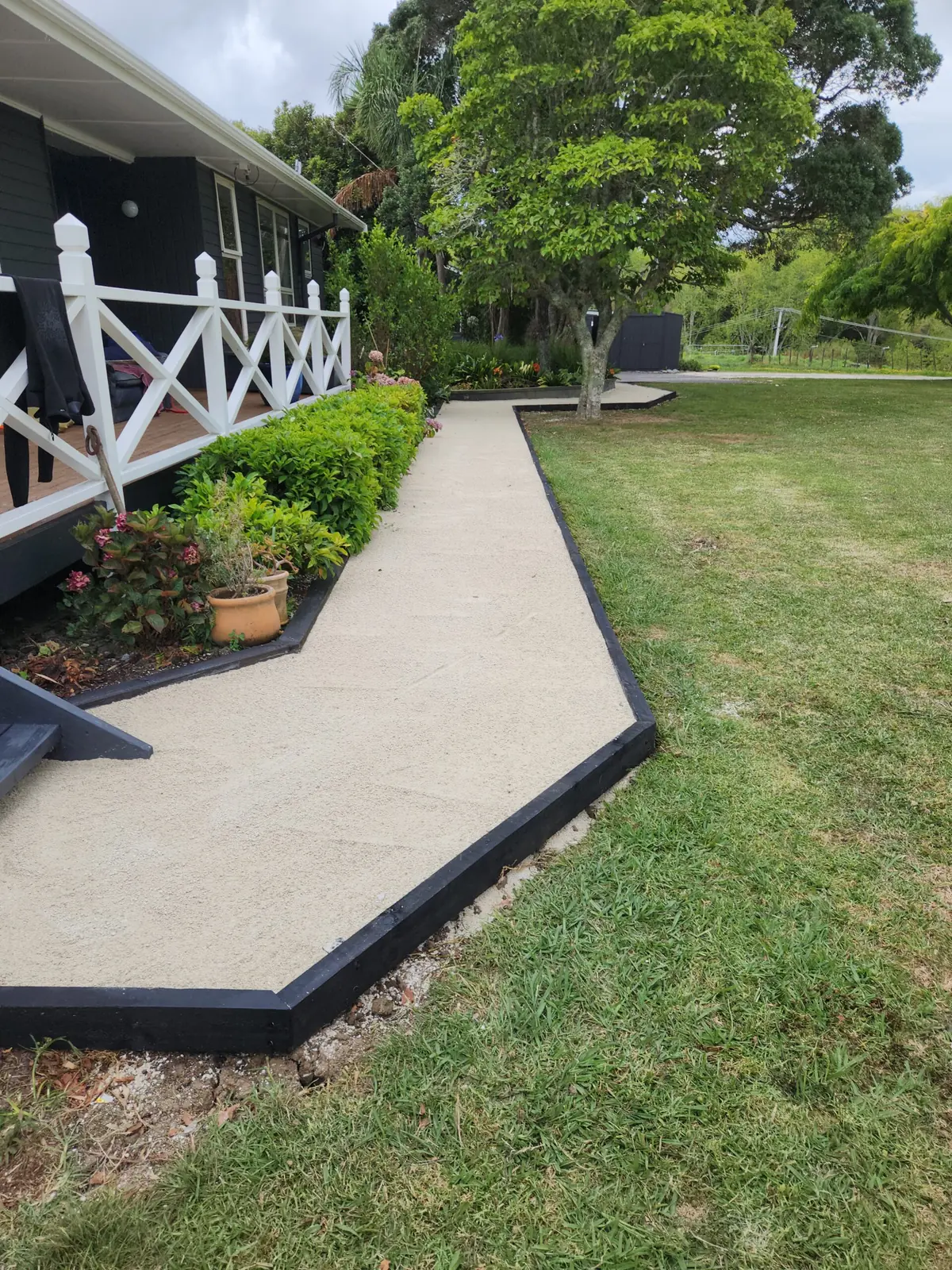 A levelled lawn and concrete path beside a West Auckland home